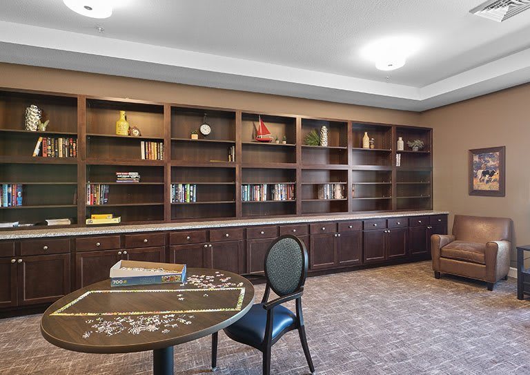A cozy library room with bookshelves, a table, and a chair.
