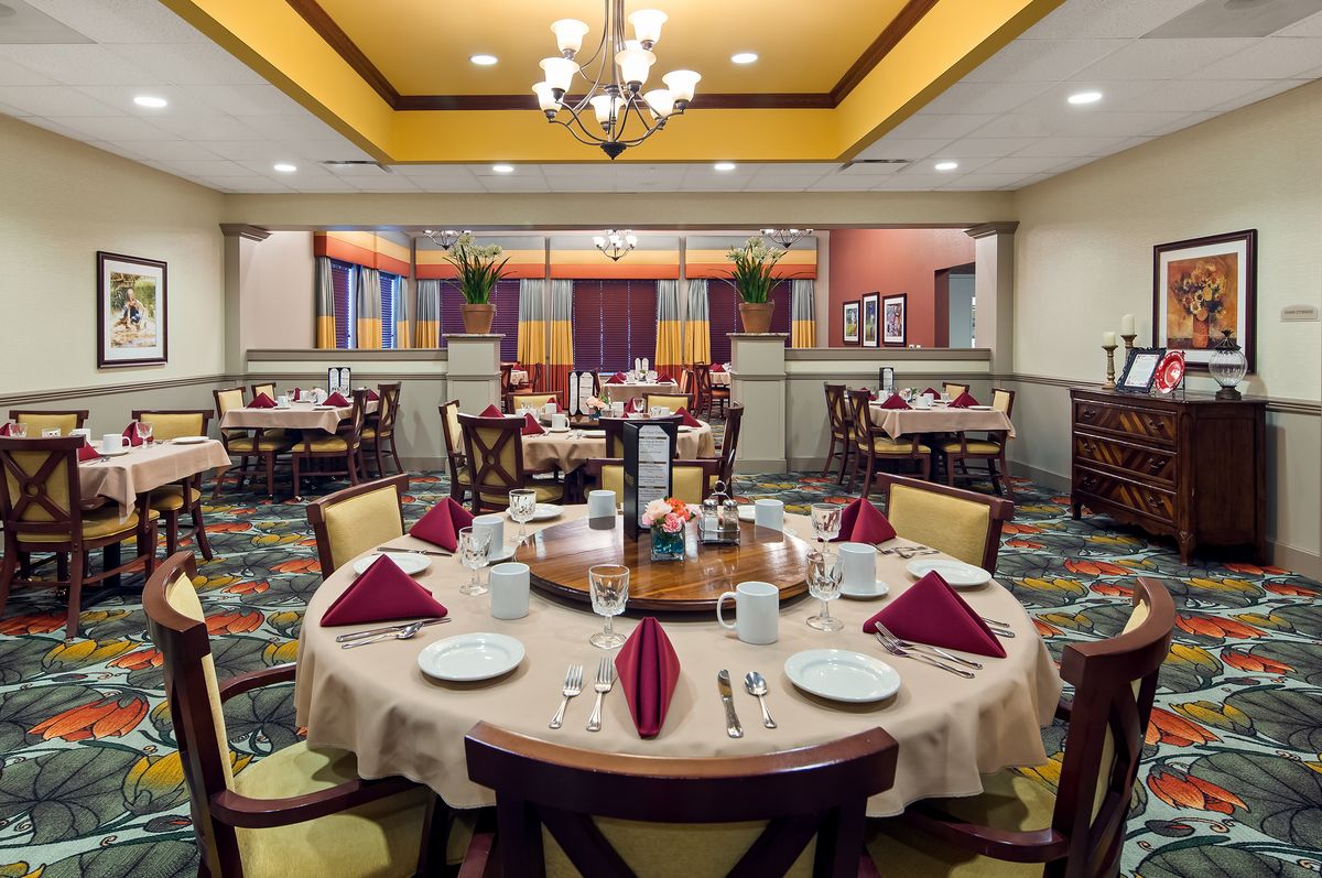 An elegant restaurant dining room with well-arranged table settings and a chandelier overhead.