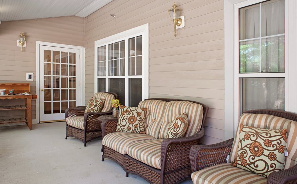 A cozy porch with wicker furniture and striped cushions.