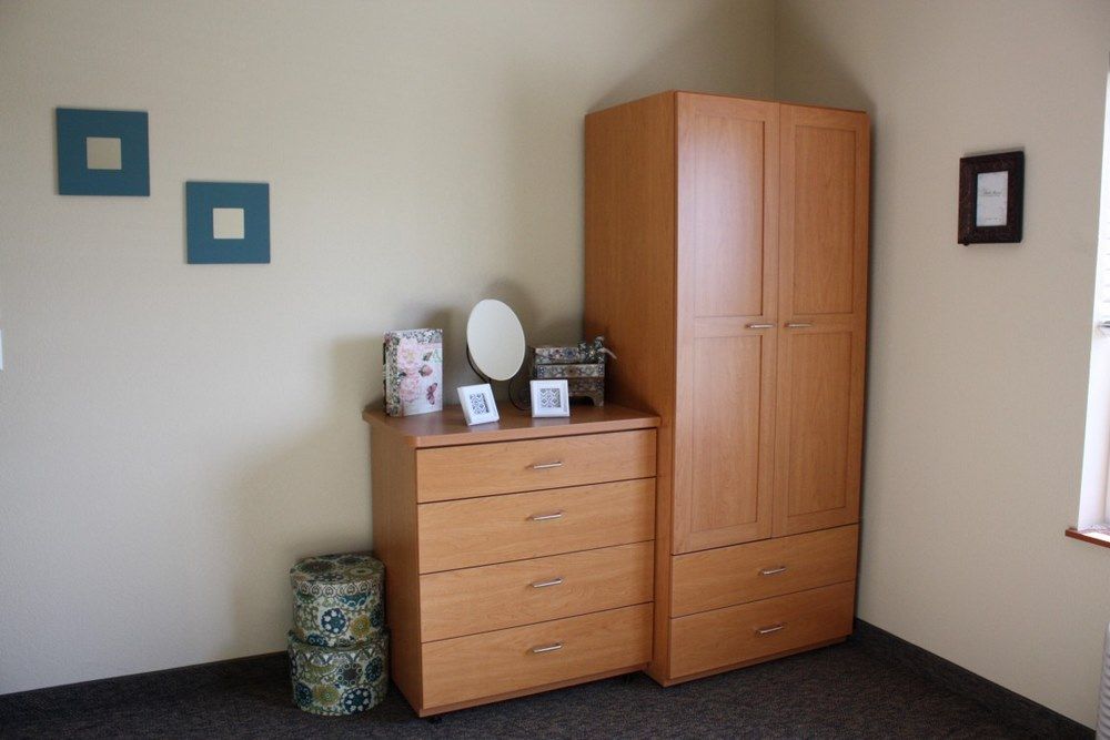 A room corner featuring a wooden dresser and wardrobe with decorative items.