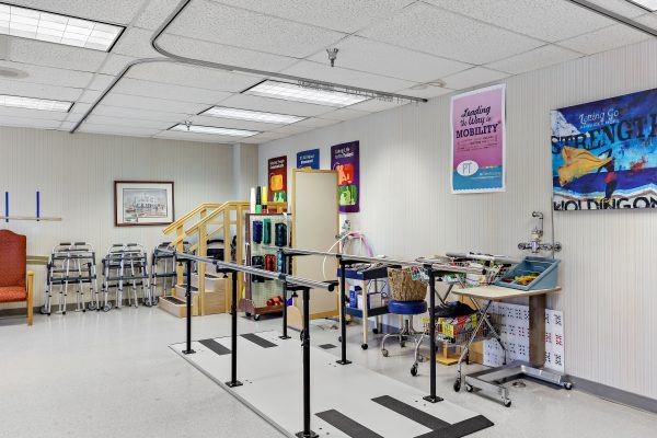 A rehabilitation therapy room equipped with parallel bars and exercise equipment.