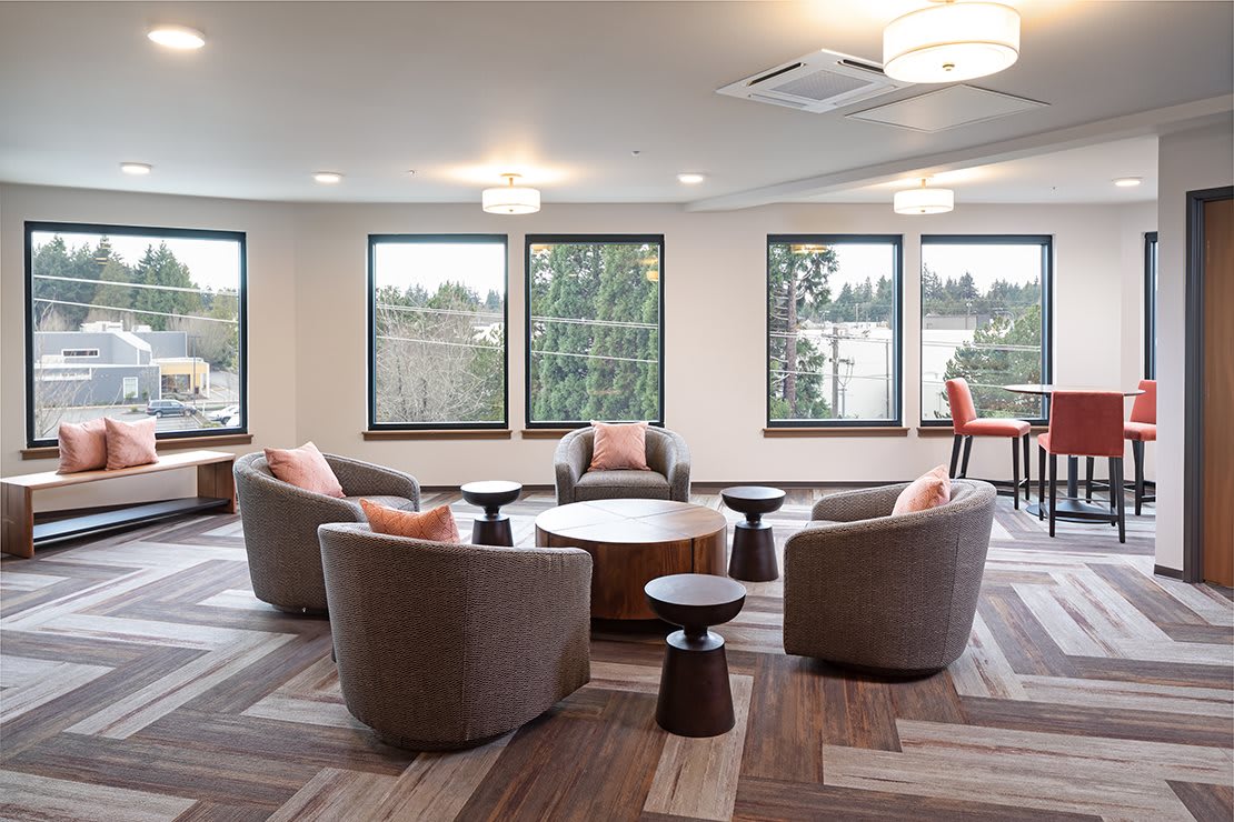 A modern living room with circular seating and large windows providing ample natural light.