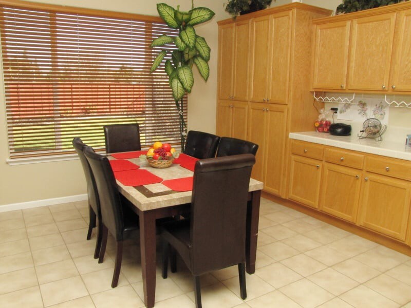 A cozy dining area with a table set for six, featuring dark chairs and a vibrant indoor plant nearby.