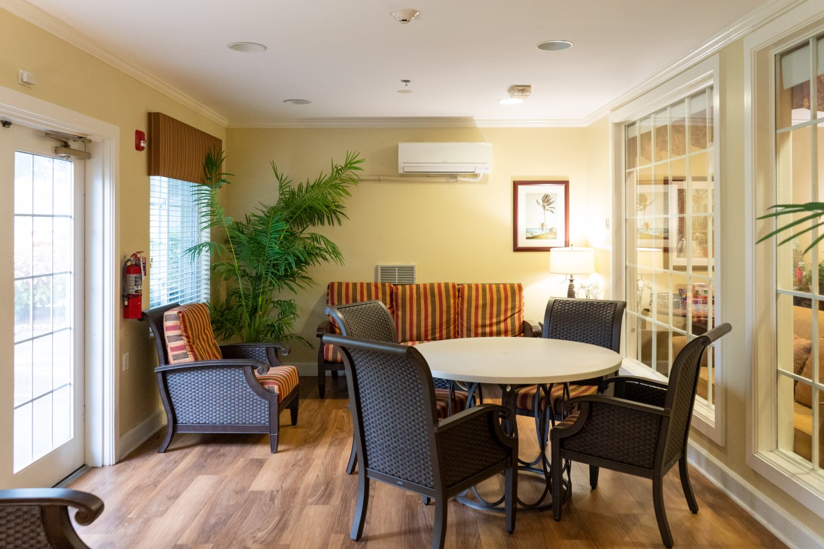 A cozy indoor lounge with a round table and chairs, complemented by a lush green plant and warm lighting.