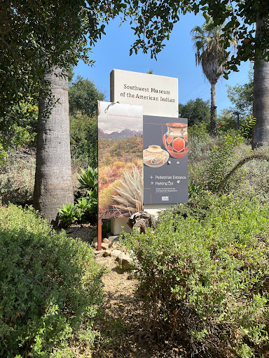 A sign at the entrance of a science museum, surrounded by lush greenery.