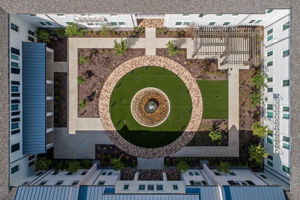 Aerial view of a symmetrical courtyard featuring a central fountain and landscaped pathways.