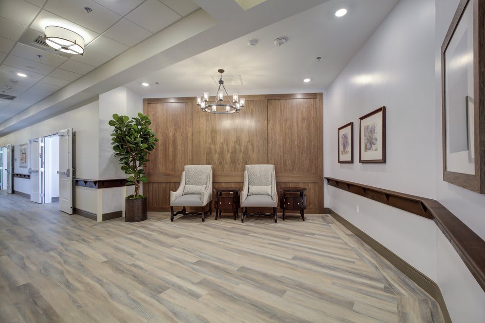 A stylish lobby area with two chairs, a chandelier, and wooden paneling.