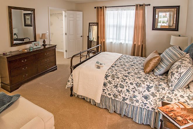 A cozy bedroom with a neatly made bed, dresser, and window.