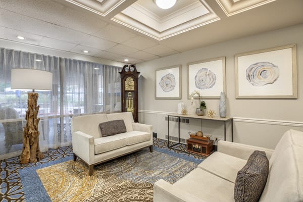 A cozy living room featuring elegant decor with sofas, a grandfather clock, and framed artwork on the walls.