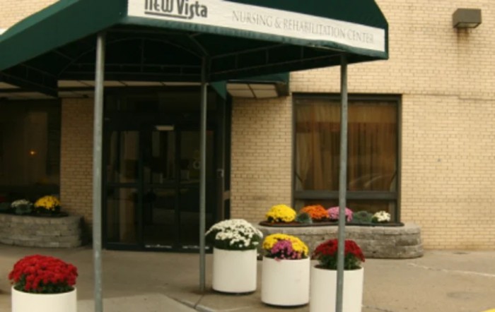An entrance to a building with an awning and potted flowers.