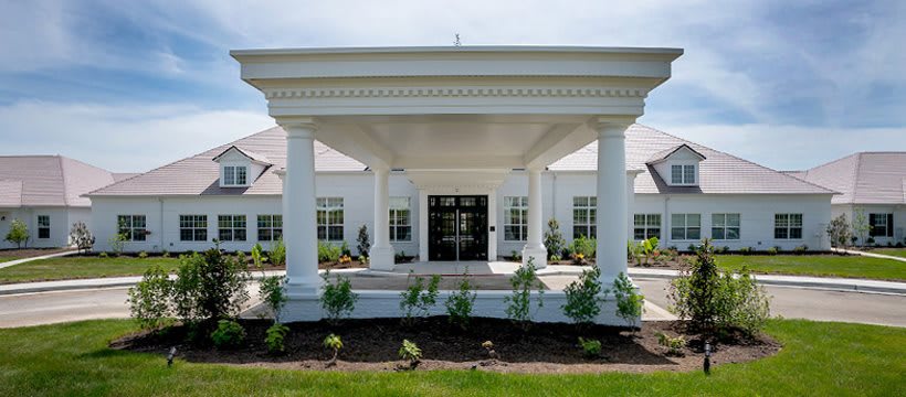 A grand building entrance featuring large columns and neatly arranged landscaping.