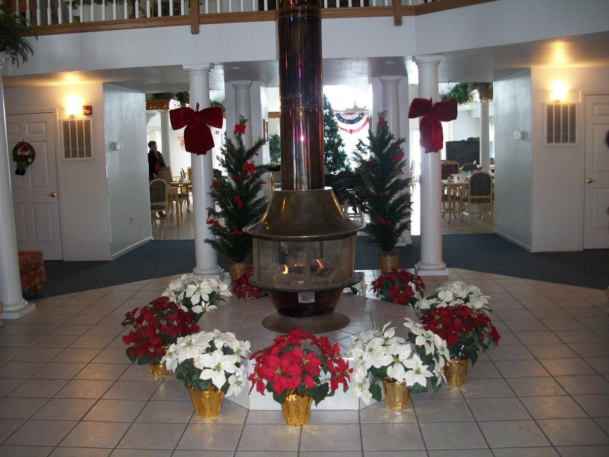 A festively decorated interior with a central fireplace surrounded by poinsettias and holiday wreaths.
