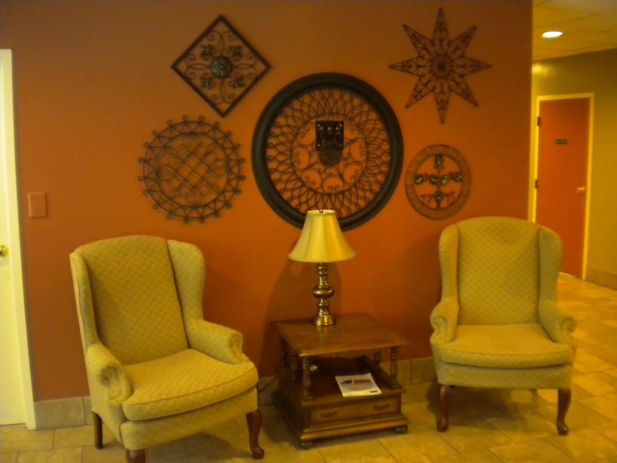 A cozy living room corner with two armchairs, a wooden table, a lamp, and decorative wall art.