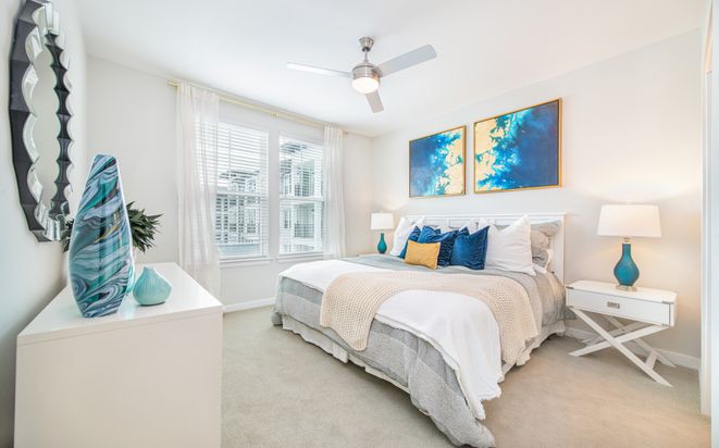 A bright and modern bedroom with neutral tones and colorful artwork.