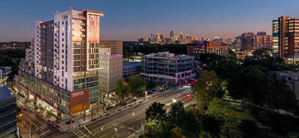 A vibrant cityscape at dusk, showcasing illuminated buildings and a bustling street.