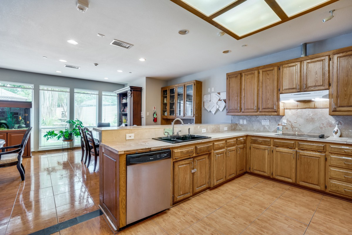 A spacious, modern kitchen with wood cabinetry and stainless steel appliances.