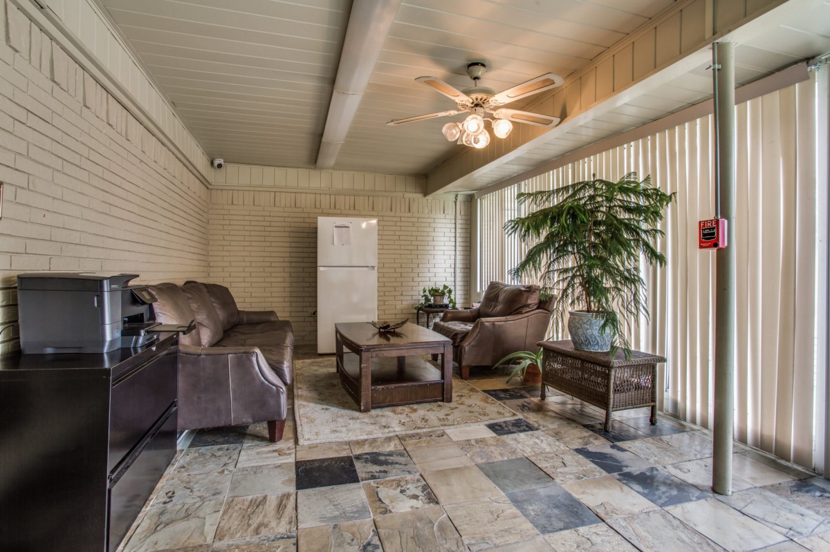 A cozy living room with comfortable seating, a ceiling fan, and ample natural light.