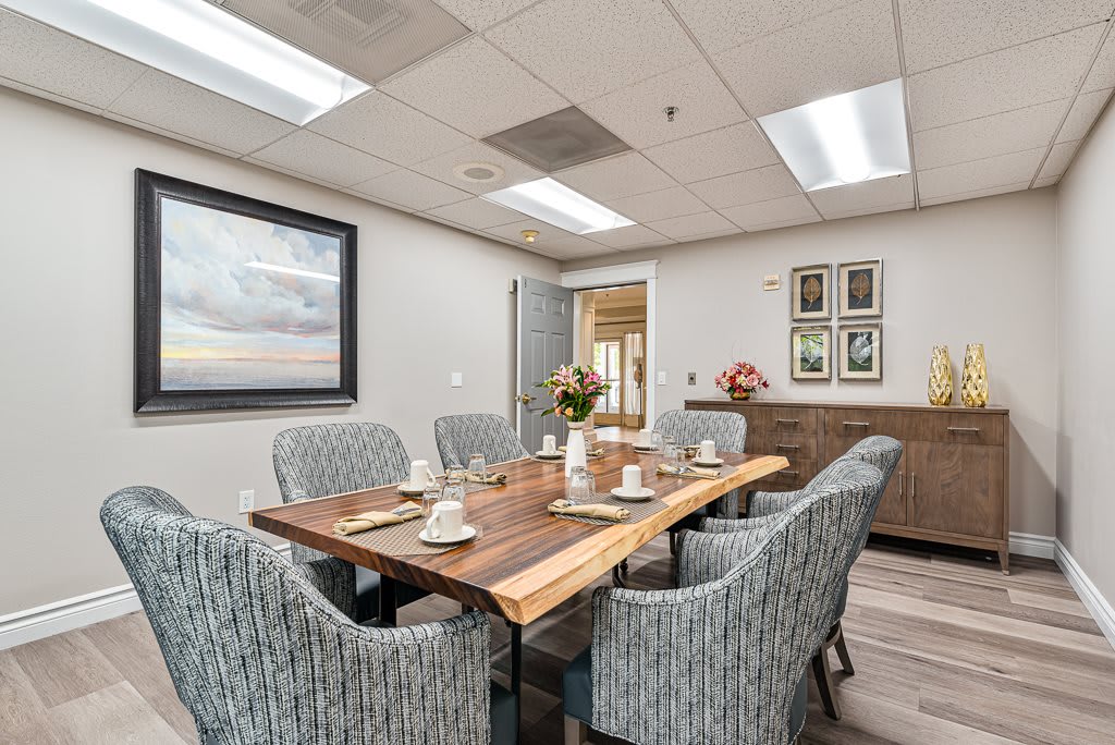 A professionally designed conference room with a large wooden table and comfortable chairs, decorated with artwork and minimalistic decor.