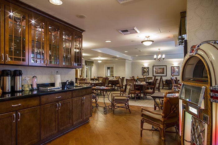 A cozy restaurant dining area with wooden tables and chairs, featuring warm lighting and elegant decor.