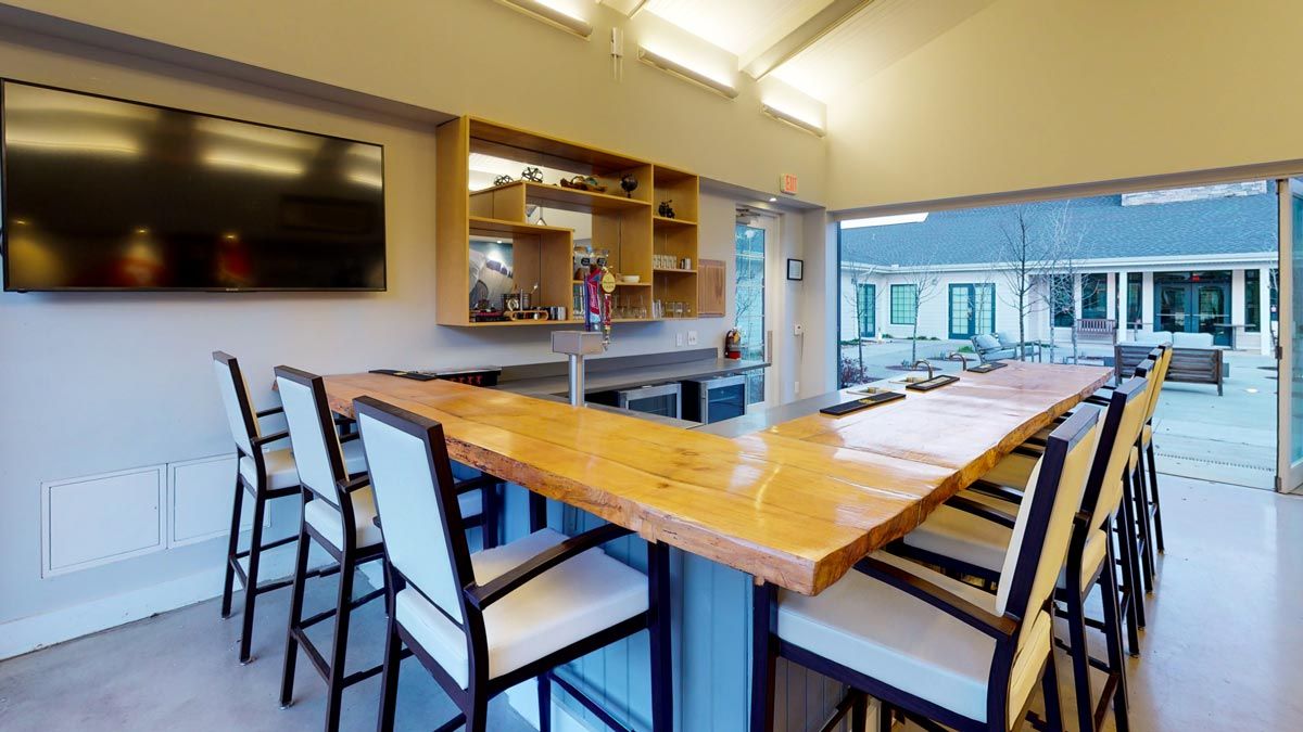 A modern indoor bar area with a wooden counter and high chairs.