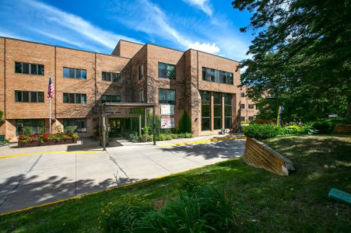 A modern brick building surrounded by greenery and under a clear blue sky.
