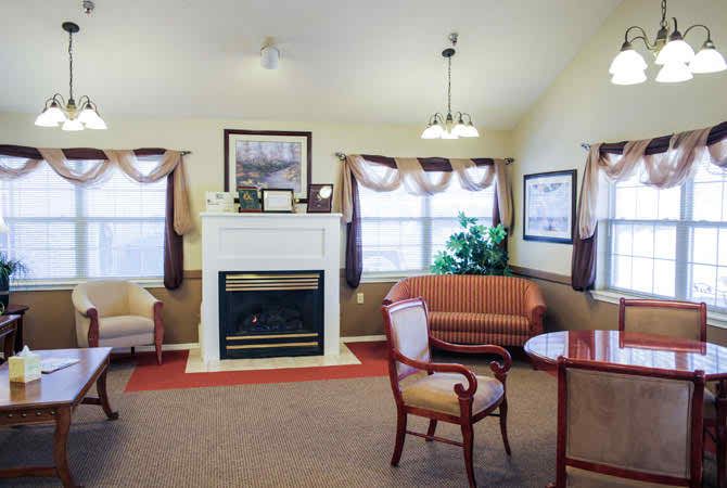 A cozy living room with a fireplace, elegant furniture, and large windows.