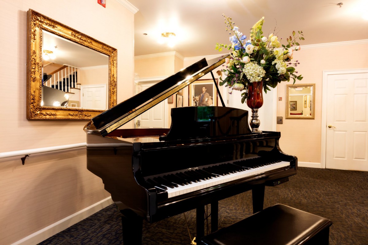 A beautifully decorated music room featuring a grand piano and a large vase of flowers.