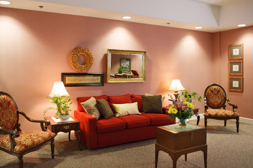 A cozy living room featuring a vibrant red couch, decorative pillows, and warm lighting.