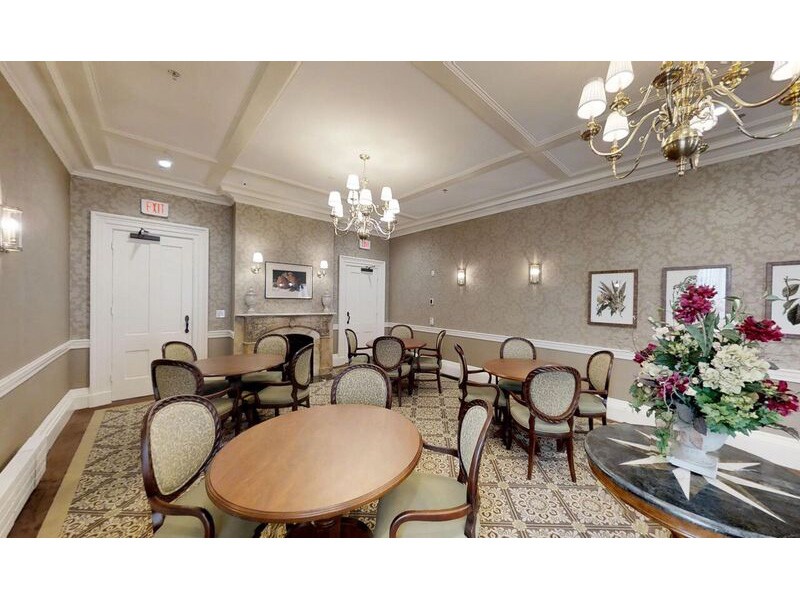 A well-decorated dining room with multiple tables and chairs, an elegant chandelier, and tasteful wall art.