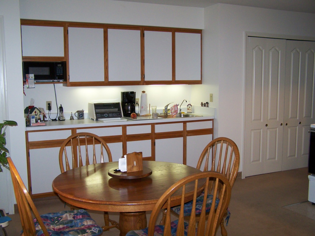 A kitchen and dining area featuring a wooden table with chairs, cabinets, and various appliances.