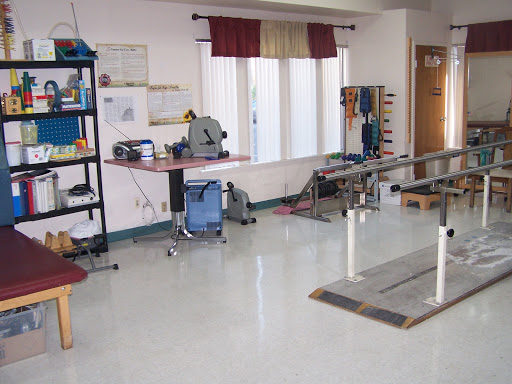 A well-equipped physical therapy room featuring rehabilitation equipment and a workstation.