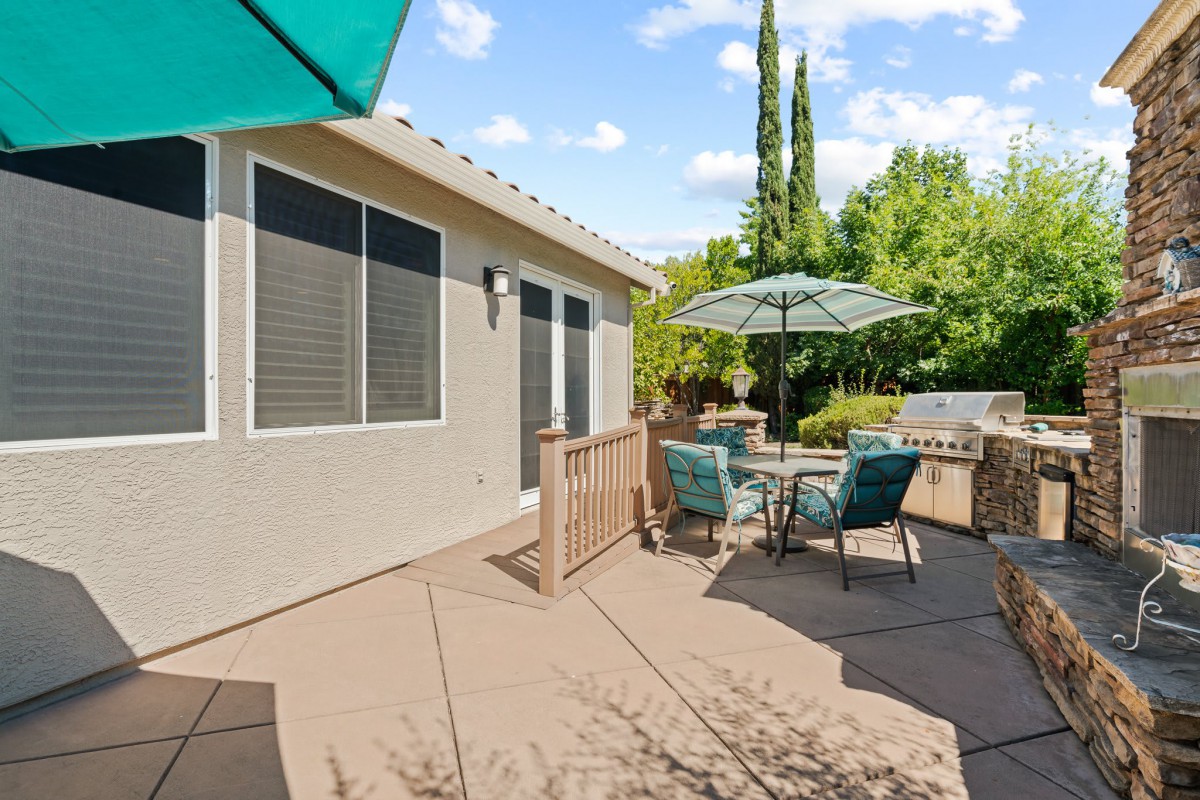 A sunny backyard patio with outdoor furniture and umbrellas.