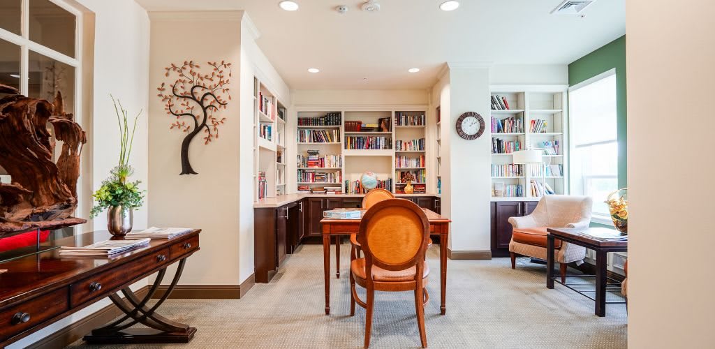 A cozy home library with bookshelves, a wooden table, and chairs.