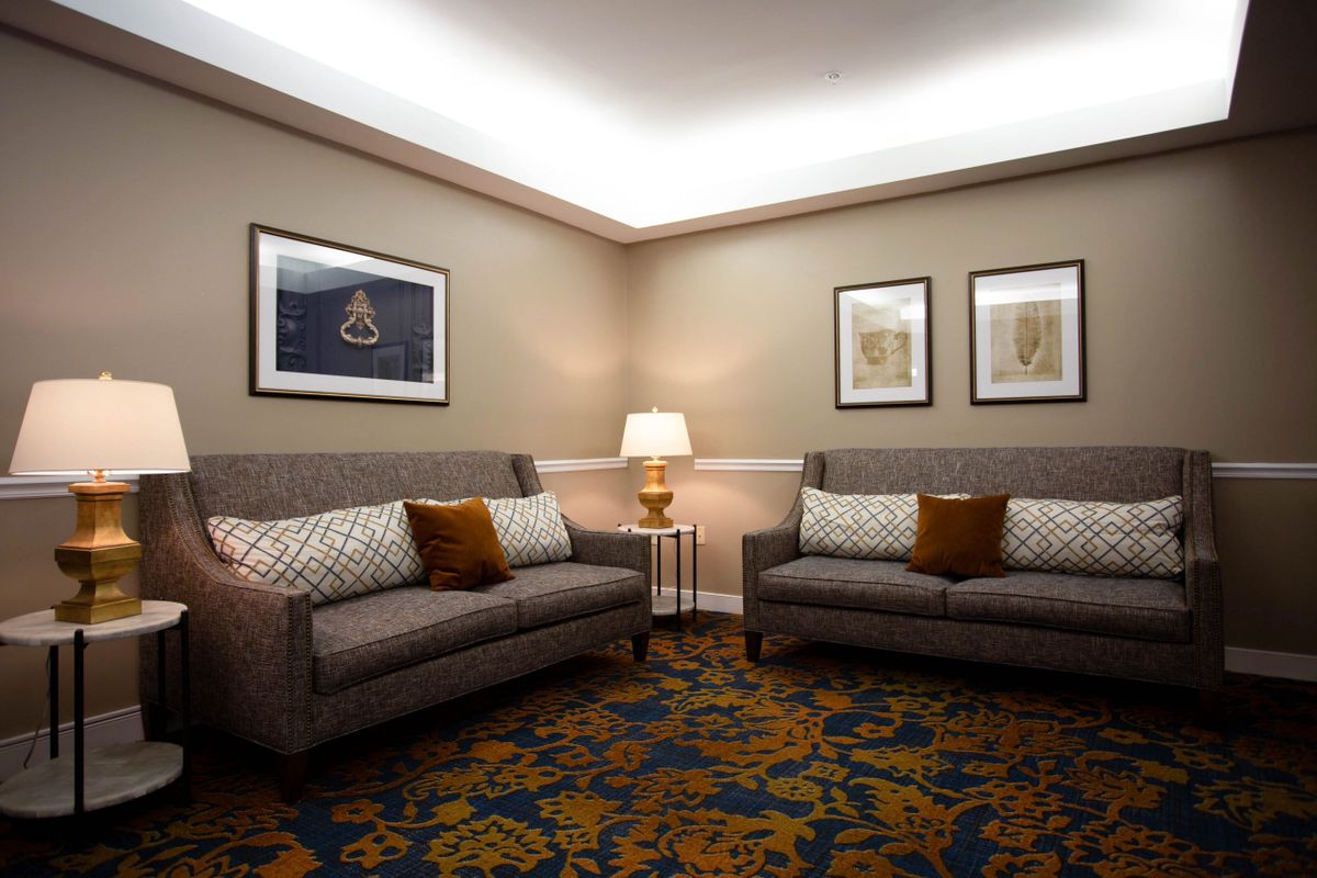 A cozy and elegantly decorated living room with two sofas, a central lamp, and framed artwork on the walls.