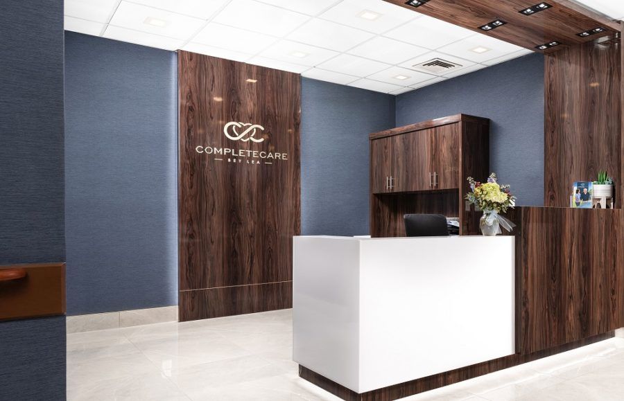 A modern and minimalist reception area featuring wooden paneling and a sleek white desk.