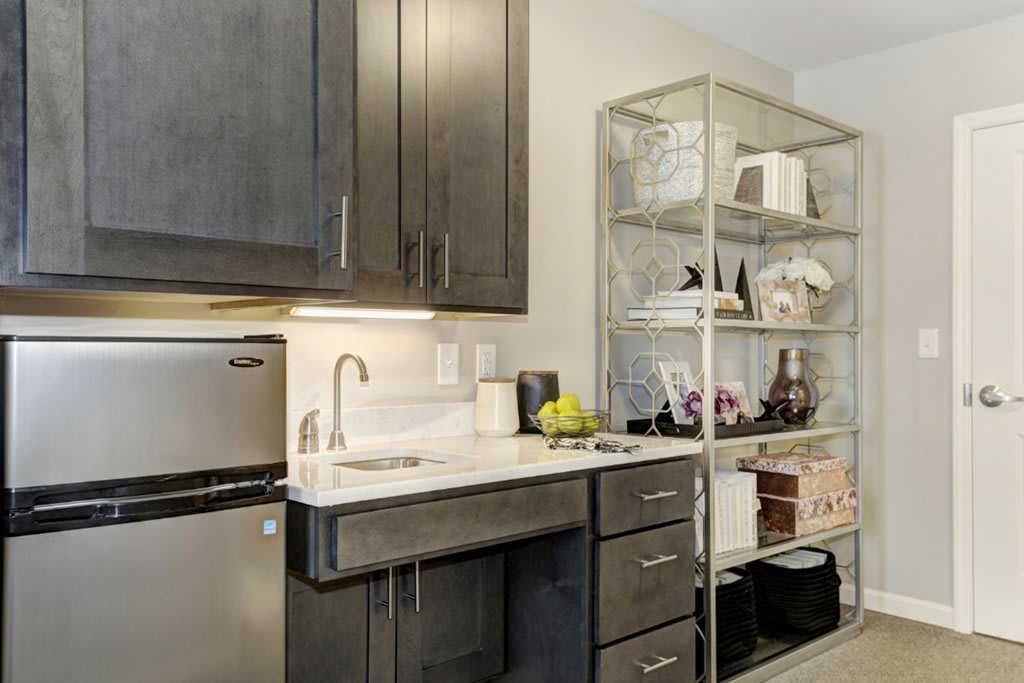 A modern kitchen with dark cabinets, a stainless steel sink, and an open shelving unit displaying various items.