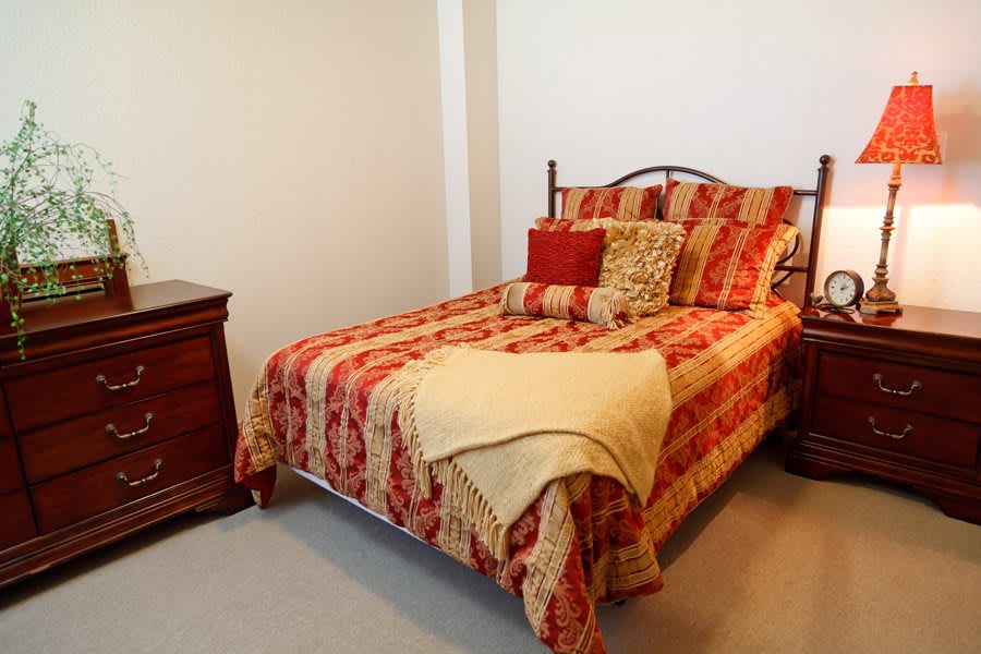 A neatly made bed in a cozy bedroom setting with warm colors and wooden furniture.