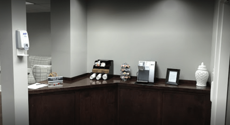 An office coffee station with cups and a coffee machine on a counter.