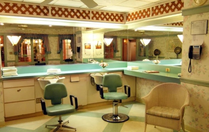 A vintage-style beauty salon with turquoise chairs and mirrored walls.