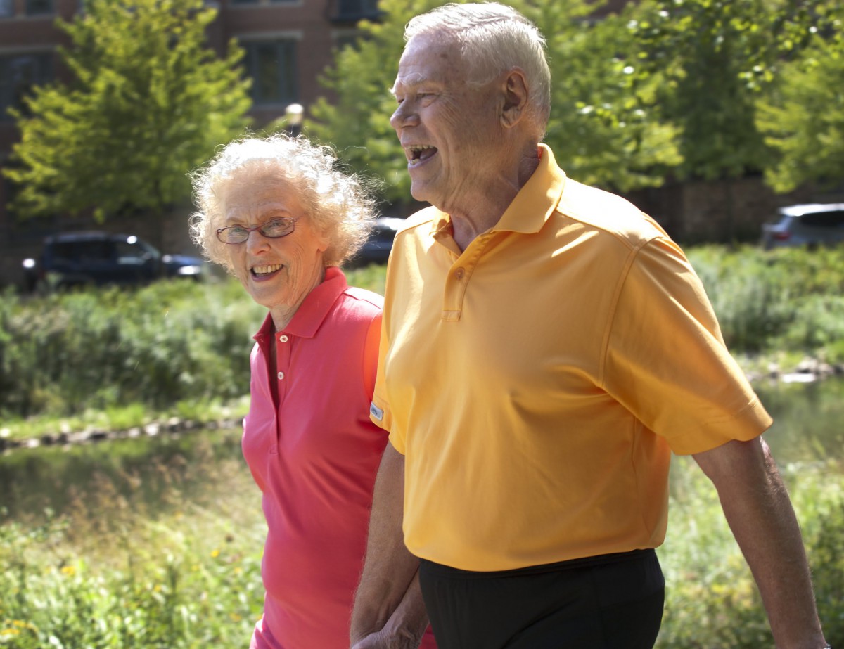 A joyful older couple enjoying a walk outdoors on a sunny day.