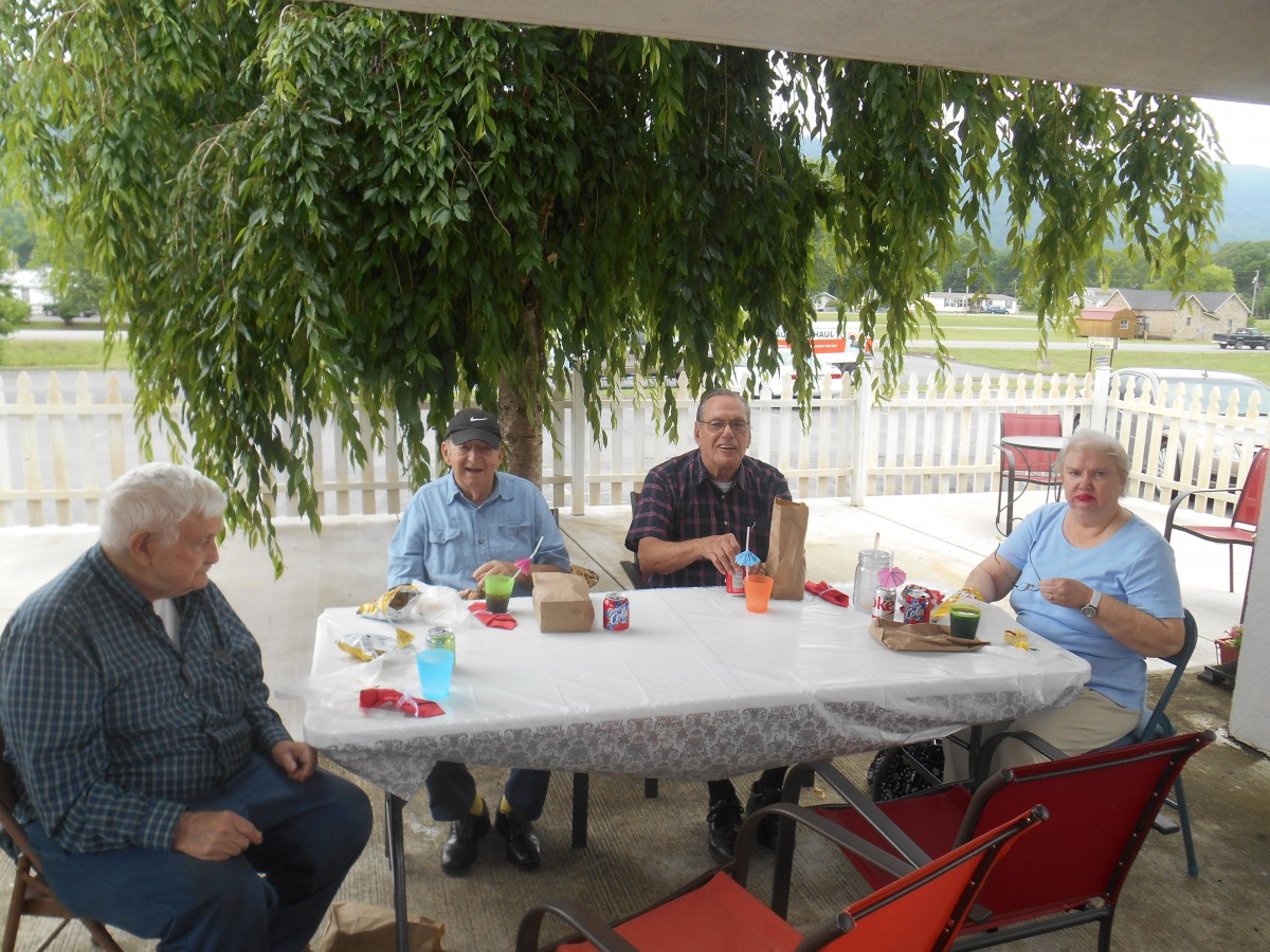 A group of people sitting around a table on a patio, enjoying an outdoor gathering.