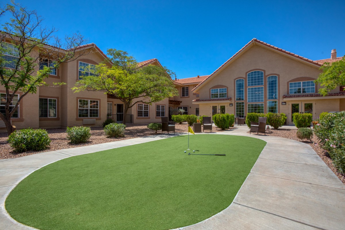 A modern building with a manicured lawn and clear blue sky.