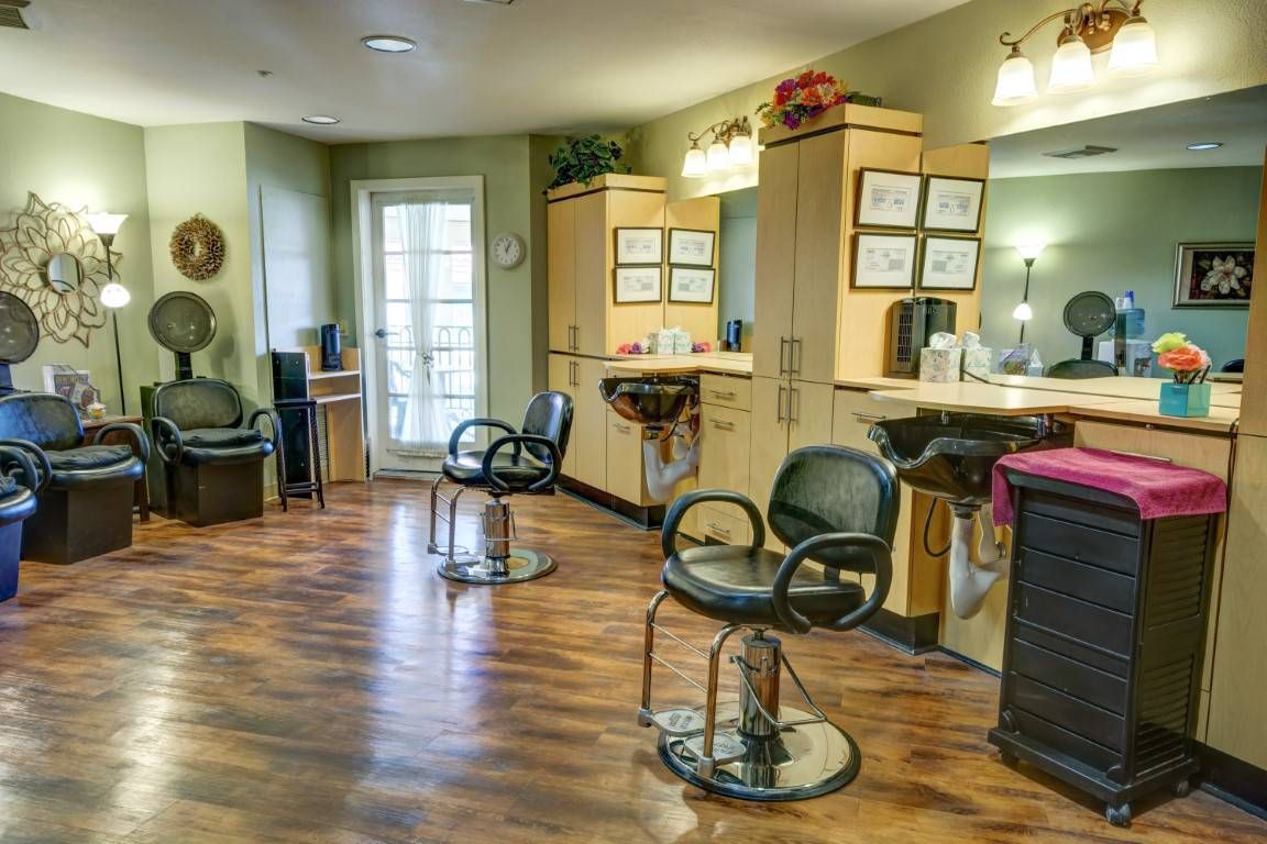 A cozy barbershop interior with salon chairs and mirrors, featuring a warm wooden floor and soft lighting.