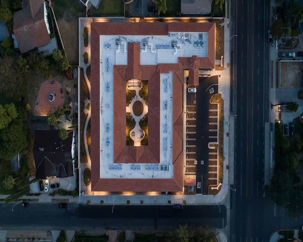 Aerial view of a well-lit building at night, showcasing its rooftop design and surrounding urban environment.