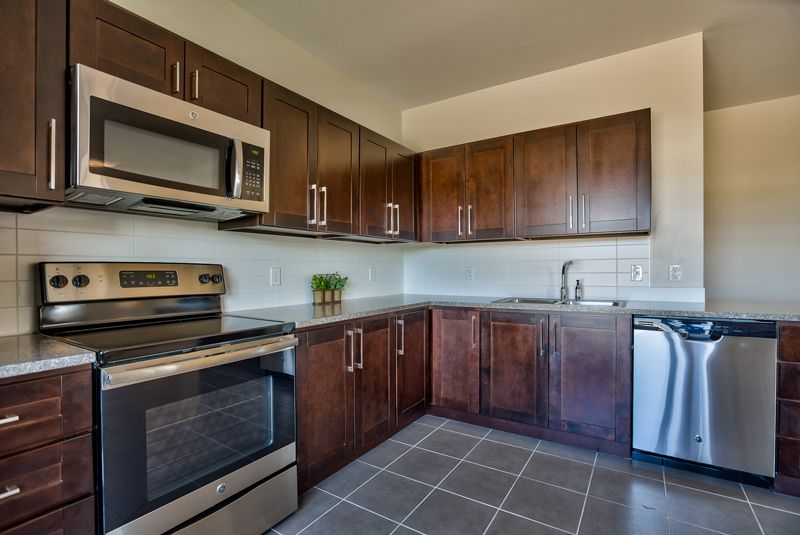 A modern kitchen with stainless steel appliances and dark wood cabinets.