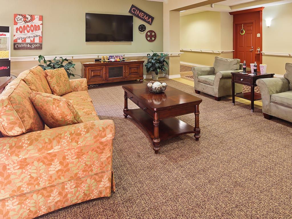 A cozy living room with a sofa, armchair, coffee table, and a television mounted on the wall.