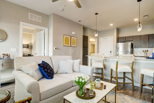 A stylish and modern living room featuring a cozy sofa, decorative accents, and an open kitchen layout.