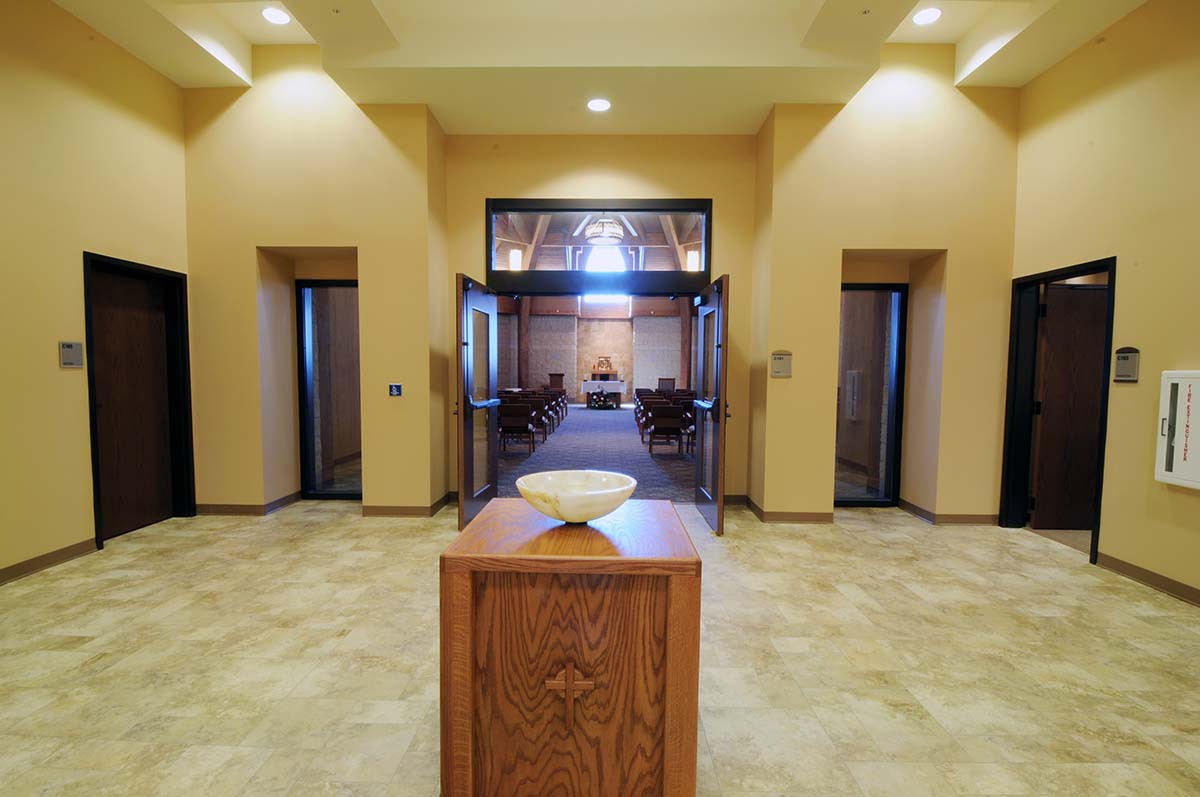 A symmetrical hallway leading to a well-lit room with wooden furnishings.