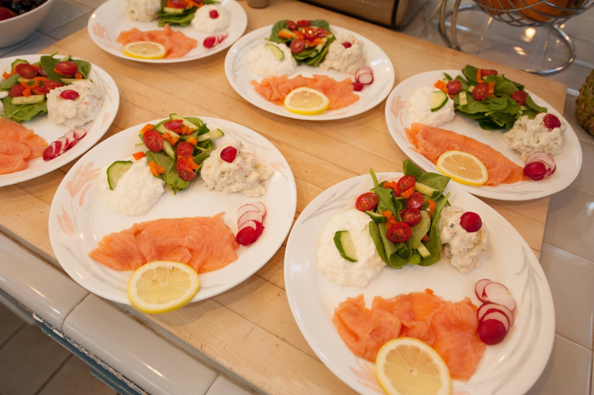Plates of smoked salmon with rice, salad, and lemon slices.