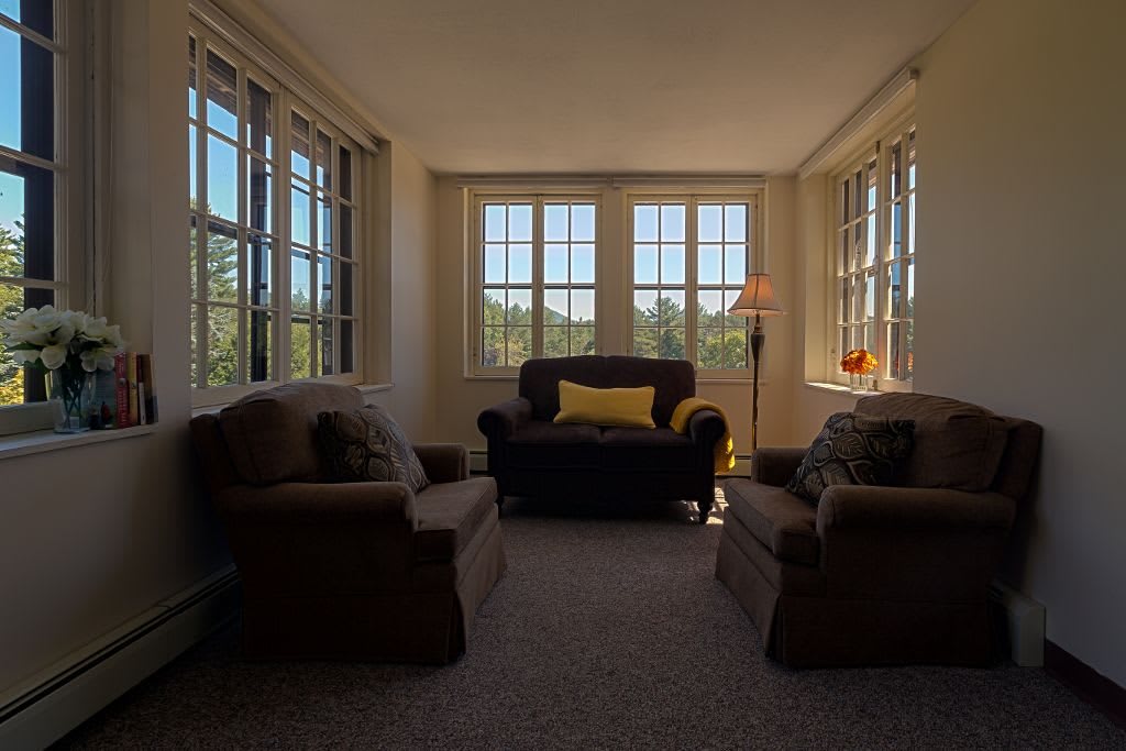 A cozy sunlit living room with comfortable seating and large windows.